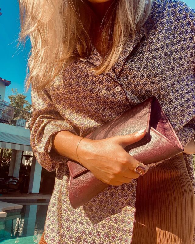 They say it’s a sign of good manners to dress according to the occasion.  Autumn has arrived and regardless of my feelings, I’ve not lost sight of all decorum. I will do the right thing and abide by the rules of nature and the inevitable change of seasons.  Autumn, I’ve dressed with your arrival in mind without losing my sense of identity. My silk Pajama shirt keeps me grounded to my British past, my vintage amethyst cocktail ring soothes my nerves, and my fitted knit skirt reminds me to walk straight and keep my eye on the future. I hold on tight to my Bordeaux color buttery soft leather clutch for moral support. Like a steadfast friend, it only gets better with wear.  Autumn, I hear you gently knocking at my door. Although I sense some familiarity with you, my go-to stiff upper lip takes over. Fortunately for you my Iranian sense of hospitality kicks in and I welcome you in and offer you some cardamom tea with walnut cookies.  “Helloooo Autumn,” I say, as I give you a half-hearted air kiss.  “Have you missed me?” you respond teasingly, with a smile.  And we pick up where we left off, circling and maneuvering around each other again.  Top & skirt: @zara 
Clutch: @fontemhandbags 
Ring: vintage.  #sabrinaazadi #fashionwriter #sabisays #pajamashirt #britishstyle #leatherclutch #fashioncolumnist #helloautumn #hellofall #luxurywriter #fall2021trends #fall2021 #fallfashion #summerlover #fallishere #londonerinoc #fashionstyle #fashionmemoirs #whatiwore #handbaglover #fallcolors #californiastyle